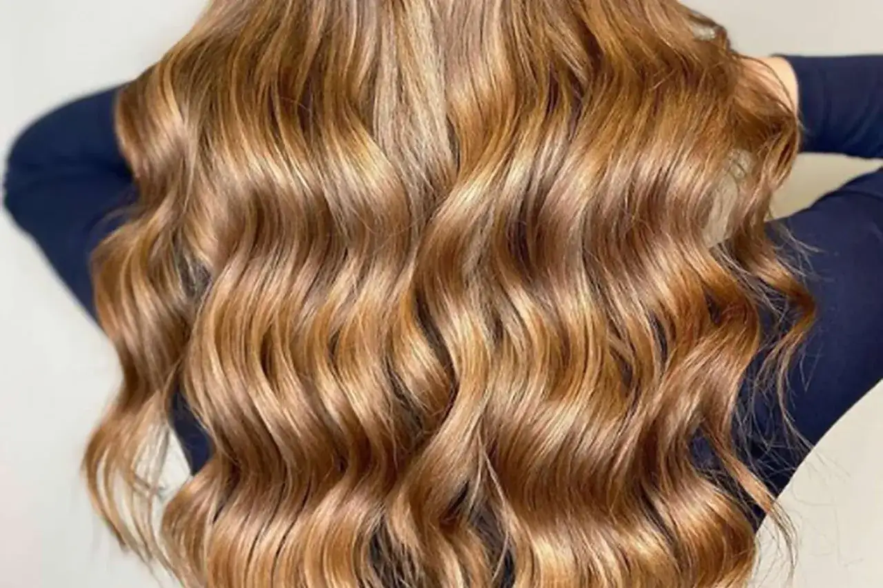 Cabello largo y ondulado con un hermoso color de pelo caramelo claro, con reflejos dorados que brillan.