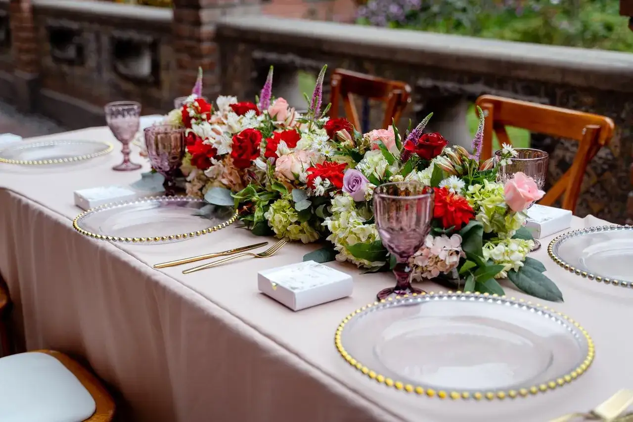 Elegante mesa de boda con centro floral vibrante, vajilla dorada y copas moradas. ¡Ideas originales para bodas que inspiran!